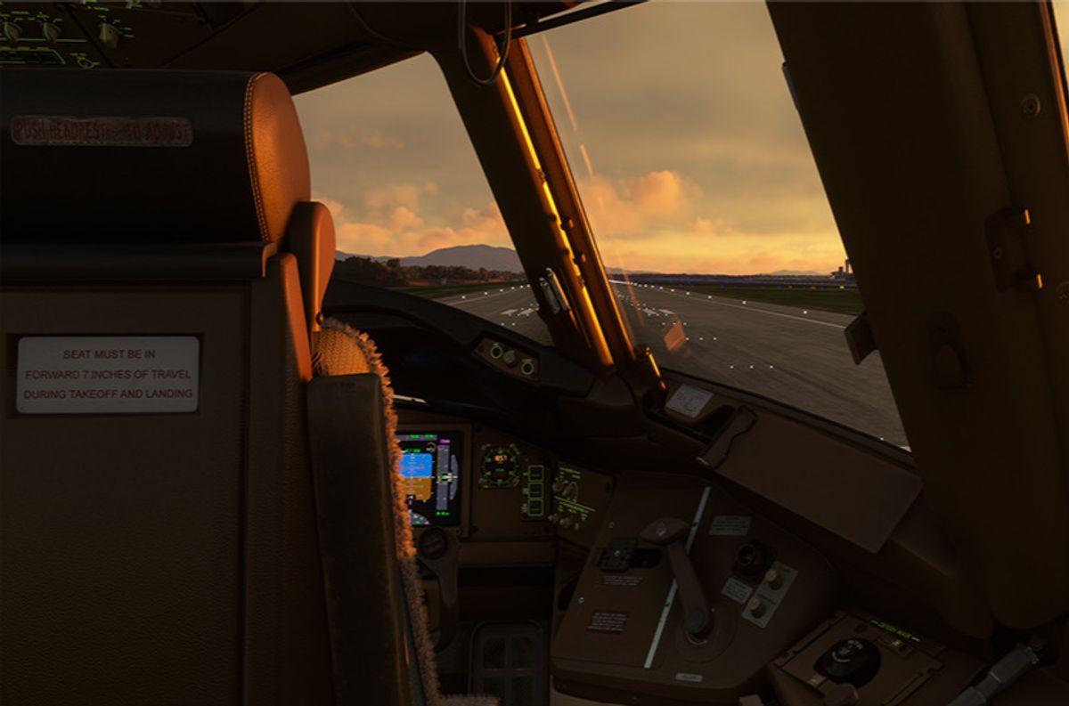 PMDG 777-300ER cockpit powered up with displays active at sunset